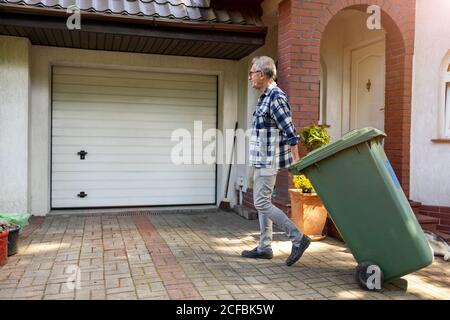 Uomo anziano che prende fuori spazzatura Foto Stock