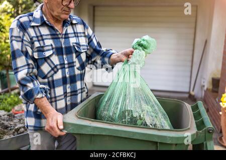 Uomo anziano che prende fuori spazzatura Foto Stock