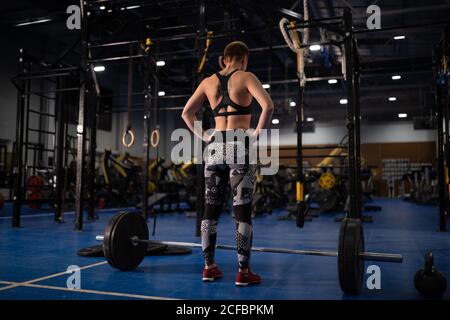 Anonimo atleta femminile che si prepara a fare deadlift esercizio durante l'allenamento in palestra Foto Stock