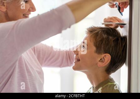 Madre che misura l'altezza del suo figlio contro il muro a. casa Foto Stock