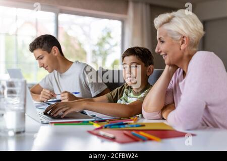 Madre che aiuta i suoi figli a fare i compiti a casa Foto Stock