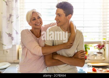 Felice madre e figlio che abbracciano sul divano Foto Stock