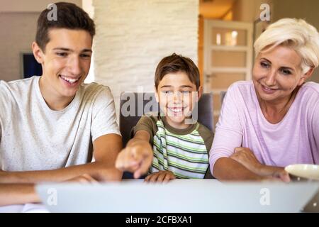 Madre con i suoi due figli che usano il computer portatile a casa Foto Stock
