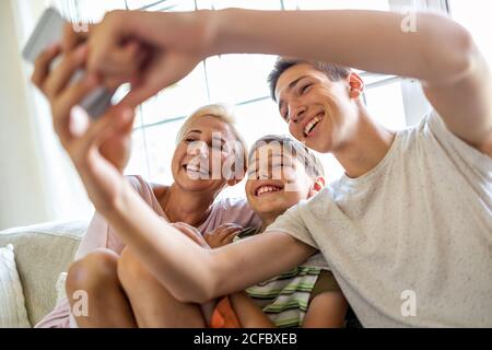 Madre con i suoi due figli che prendono selfie a casa Foto Stock