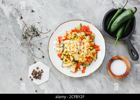 La ciotola è servita con mais, pomodori tagliati e zucchine tavola con sale e pepe Foto Stock