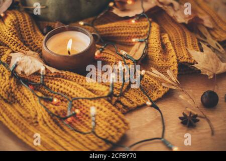Buon Ringraziamento e Ciao autunno, festeggiando le vacanze autunnali in casa accogliente. Foglie autunnali, spezie e candela su un comodo pullover lavorato a maglia in giallo caldo l Foto Stock