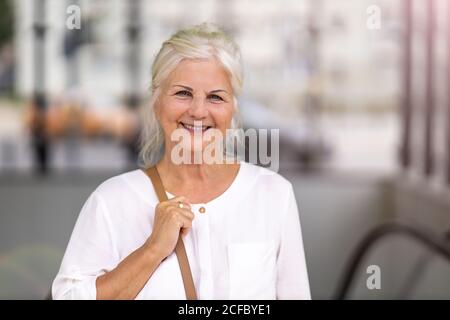 Ritratto di donna anziana sorridente in città Foto Stock