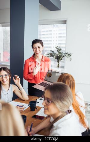 Bel giovane che lavora con il computer e sorride mentre si è in piedi in officina Foto Stock