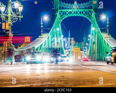 BUDAPEST, Ungheria - 14 dicembre 2019: vista sul traffico sulla piazza Fovam e il Ponte della Libertà di notte a Budapest, Ungheria. Foto Stock