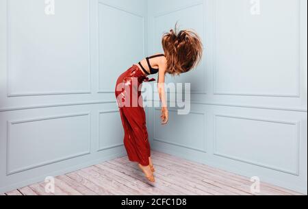 Vista laterale della ragazza ispanica che batte sul netbook mentre si siede sul comodo divano vicino al padre che naviga smartphone in salotto Foto Stock