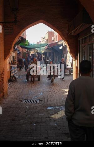 Strada laterale nel souk di Marrakech con berberi su scooter e. compagni Foto Stock