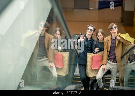 Tre fidanzate in Escalator con borse per lo shopping Foto Stock