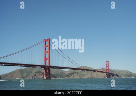 Famoso ponte sospeso Golden Gate a San Francisco in California con costa collinosa e cielo blu chiaro sullo sfondo giorno di sole Foto Stock
