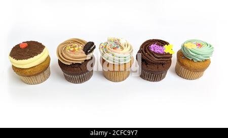 Cupcakes cioccolato e vaniglia deliziosi dolci decorati di fila su sfondo bianco Foto Stock