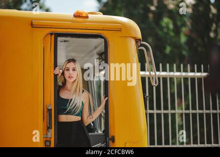 Giovane allegra bella donna bionda in piedi sul treno giallo in cabina autisti a Berlino guardando la macchina fotografica Foto Stock