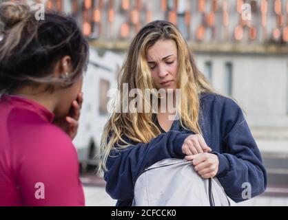 Sportivo femminile stanco con zaino in piedi sul campo sportivo insieme alla ragazza etnica dopo l'allenamento Foto Stock