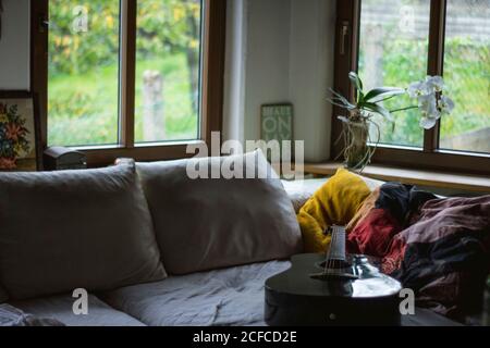 Sala lounge moderna, luminosa e accogliente, con comodo divano cuscini e chitarra in casa moderna Foto Stock