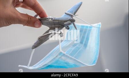 Una maschera facciale posizionata come un paracadute su un piccolo aereo giocattolo in plastica Foto Stock