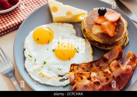 Deliziose uova fritte con pancetta e formaggio a colazione Foto Stock