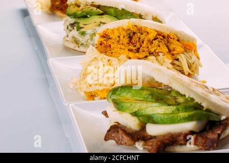 Colazione latinoamericana, in particolare in paesi come il Venezuela e la Colombia, Arepas con diversi ingredienti per riempire come pollo, carne, avocado, formaggio Foto Stock