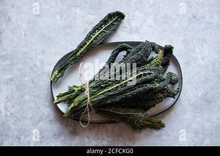 Dall'alto mazzo di foglie di kale verde sul piano portapaziente grigio Foto Stock