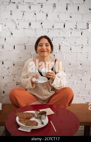 Donna pacifica bere caffè mentre riposa a casa Foto Stock