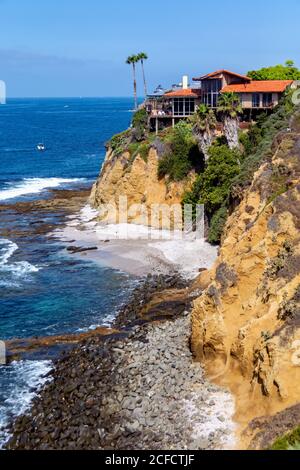 Vista sull'oceano e sulle scogliere, sulle piscine con maree, sulle onde del mare e sulle rocce, con case sulla scogliera e spiaggia rocciosa dall'alto su un promontorio. Foto Stock