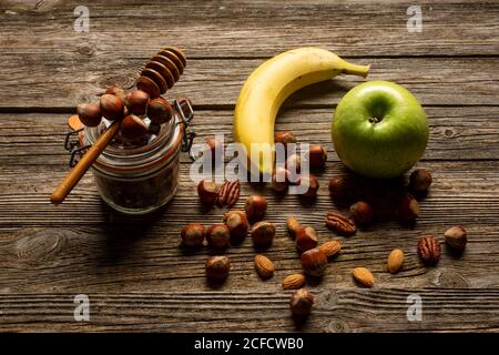 Mela e banana con noci su tavola di legno Foto Stock