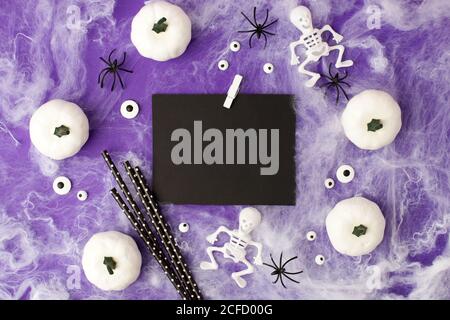 Halloween vacanza vuoto con decorazione festa, ragni neri, zucche bianche, scheletri e occhi, web su viola tradizionale. Disposizione piatta, vista dall'alto. Spazio per Foto Stock