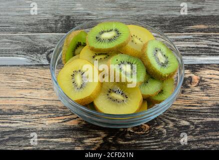 Crudi fresco giallo dorato e verde kiwi fette di frutta in recipiente in vetro sul tavolo Foto Stock