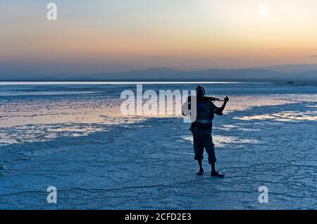 Guardia di sicurezza con Kalashnikov al lago salato Assale al tramonto, Hamadela, Danakil depressione Afar triangolo, Etiopia Foto Stock