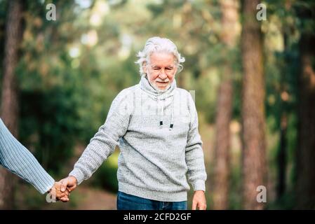 Assistenza e malattia alzheimer problemi per anziani - uomo anziano tenendo le mani e camminare nella foresta per godere la natura attività di svago all'aperto Foto Stock