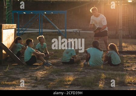 Allenatore di fitness maschile che dà istruzioni ai bambini a un bootcamp Foto Stock