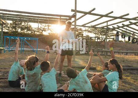 Allenatore di fitness maschile che dà istruzioni ai bambini a un bootcamp Foto Stock