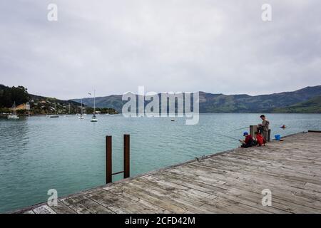 Ragazzi che pescano nel porto di Akaroa Foto Stock