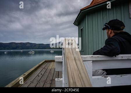 Turista sul molo nel porto di Akaroa Foto Stock