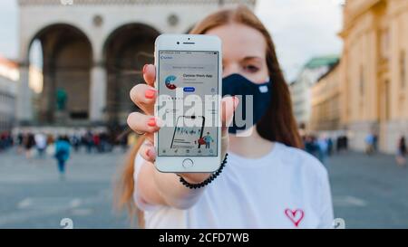 Donna dai capelli rossi con l'app di avvertimento Corona sull'iphone di Monaco Su Odeonsplatz Foto Stock