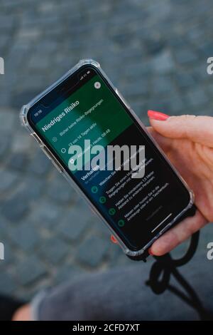 Donna dai capelli rossi con app di avvertimento Corona su Odeonsplatz a Monaco / istruzioni per l'applicazione di avviso Corona Foto Stock