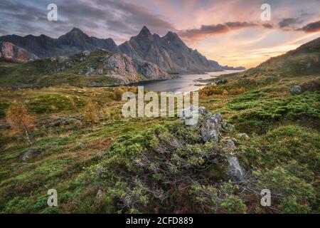 Tramonto sul fiordo di pietra autunnale, sullo sfondo il Mare nordico e il massiccio sommitale di Himmelstindan, Lofoten, Nordland, Norvegia Foto Stock