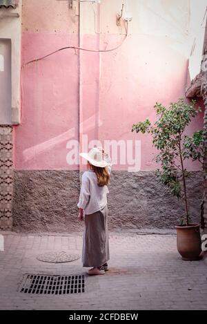 Marrakech, Marocco - Ottobre, 23, 2018: Vista laterale di una donna senza volto turista in cappello elegante camicia e gonna a piedi al vicolo a dondolo Foto Stock