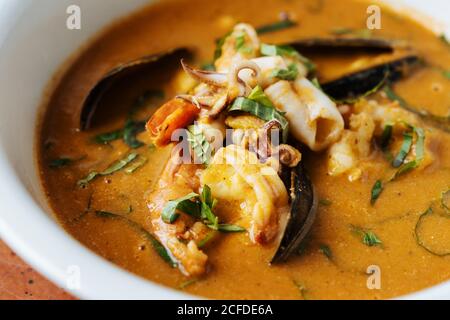 Da sopra il ragù di closeup con cozze di pesce bollito polpo piccolo ed erbe sul piatto nel ristorante Foto Stock