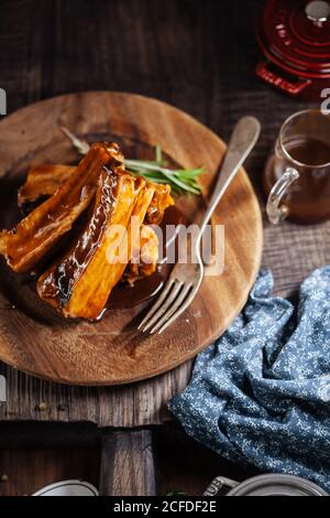 Costolette di maiale grigliate su piatto di legno Foto Stock