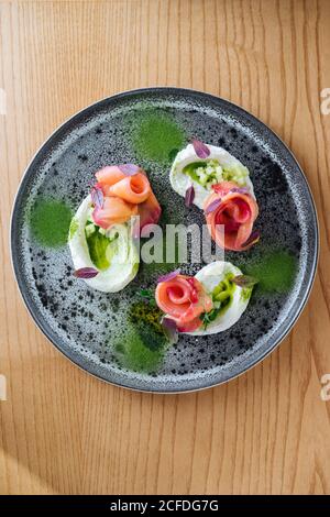 Involtini di salmone con cipolla ed erbe servite su piatto rustico su tavolo di legno Foto Stock