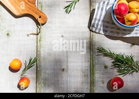 Tavolo da giardino decorato con albicocche e rosmarino, con spazio centrale per la copia Foto Stock