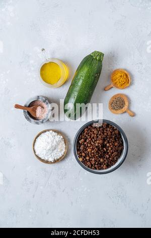 Vista dall'alto degli ingredienti per gli hamburger vegetariani di zucchine e lenticchie con spezie su sfondo bianco Foto Stock