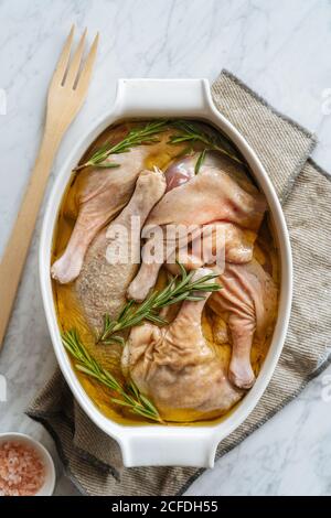 Cosce di pollo marinate non cotte in una teglia da forno Foto Stock