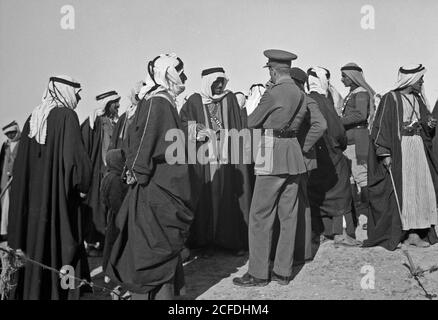 Didascalia originale: Un pranzo tribale al posto della cavalleria a Tel-el-Meleiha 20 miglia a nord di Beerseba Gennaio 18 1940. Ospiti in piedi circa in conversazione dopo il pasto vicino - posizione: Israele ca. 1940 Foto Stock