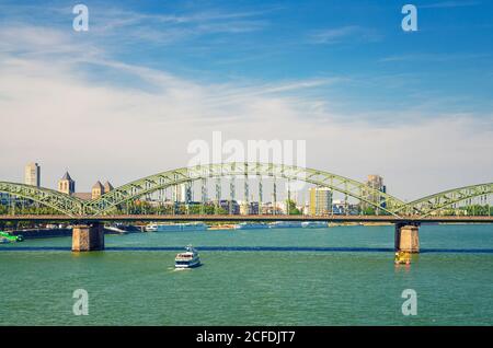 Il ponte di Hohenzollern o Hohenzollernbrucke attraverso il fiume Reno con barca turistica a vela sull'acqua, pedone e ponte ferroviario in acciaio, centro di Colonia, Nord Reno-Westfalia, Germania Foto Stock