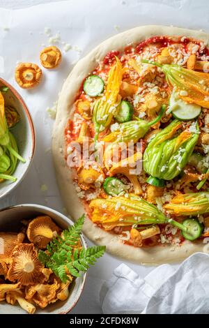 Ingredienti per pizza vegetariana a base di fiori di zucchine e funghi su carta da forno Foto Stock