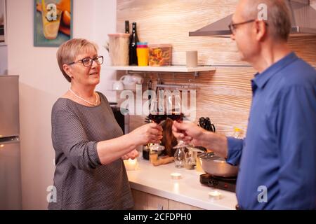 Coppia senior che festeggia l'anniversario del rapporto con il vino rosso. Coppia anziano in amore che parla avendo una conversazione piacevole durante il pasto sano. Foto Stock